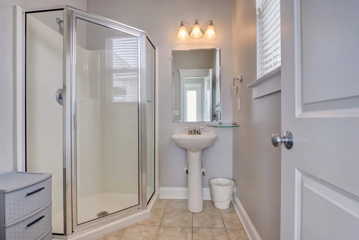 A modern bathroom with a glass shower enclosure, a sink and mirror, and a neat storage unit—bright, clean, and designed for rejuvenating routines.