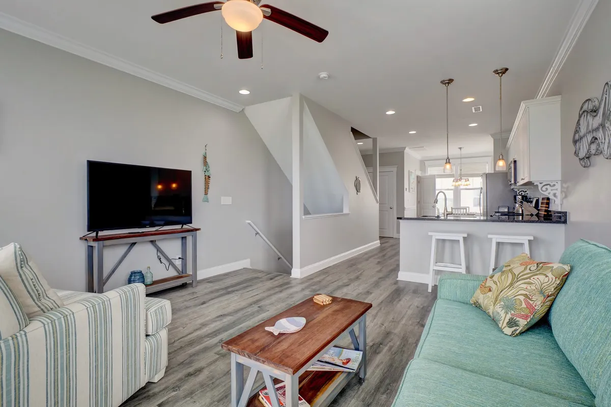 A comfortable lounge area with a sofa adorned with colorful cushions, a coffee table with magazines, and a television setup, radiating a casual and welcoming vibe perfect for relaxation or socializing.