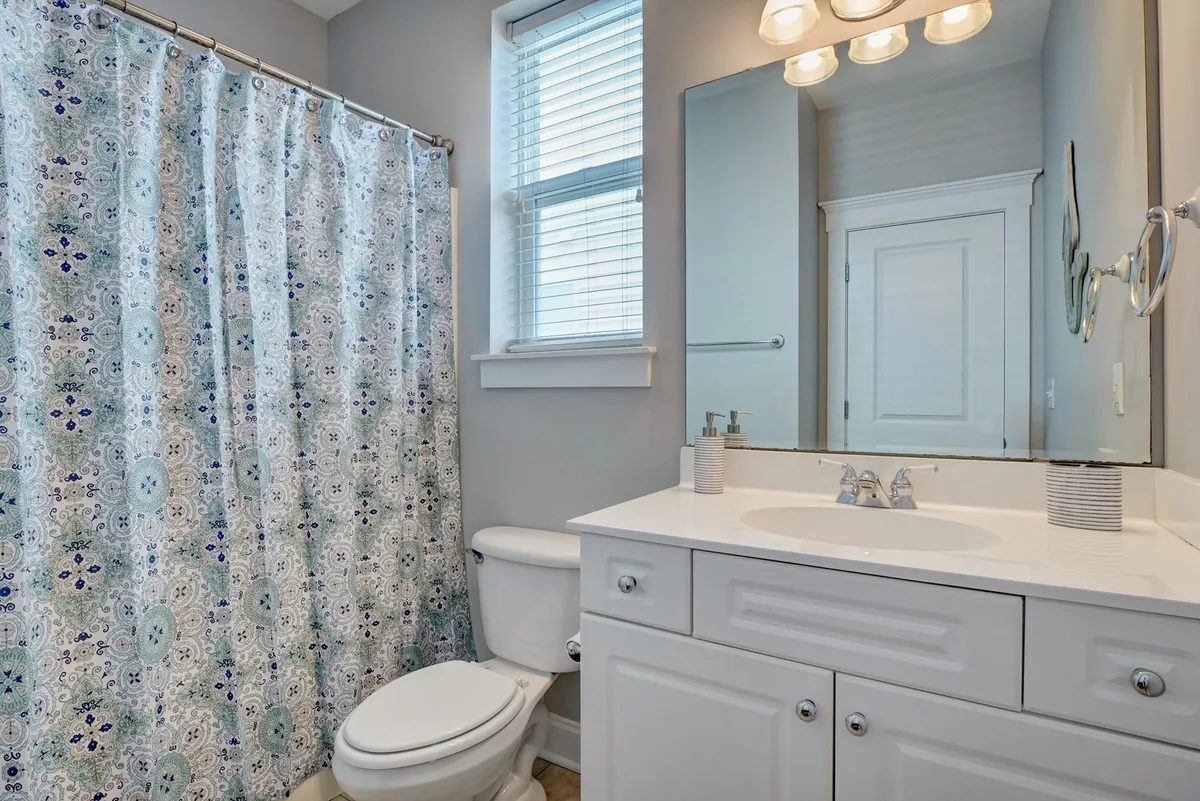 A tastefully updated full bathroom featuring a shower curtain, vanity with sink, and a mirror. The space is clean and modern, offering a relaxing spot for personal care and refreshment.