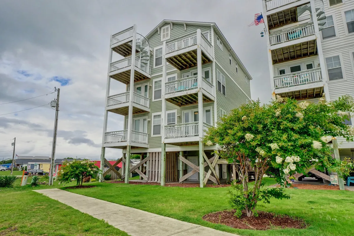An exterior perspective showcasing the multi-level structure of the home, with prominent balconies and decks overlooking a green lawn. The image captures the connection between multiple outdoor decks and hints at the inviting spaces for relaxing or gathering outside.